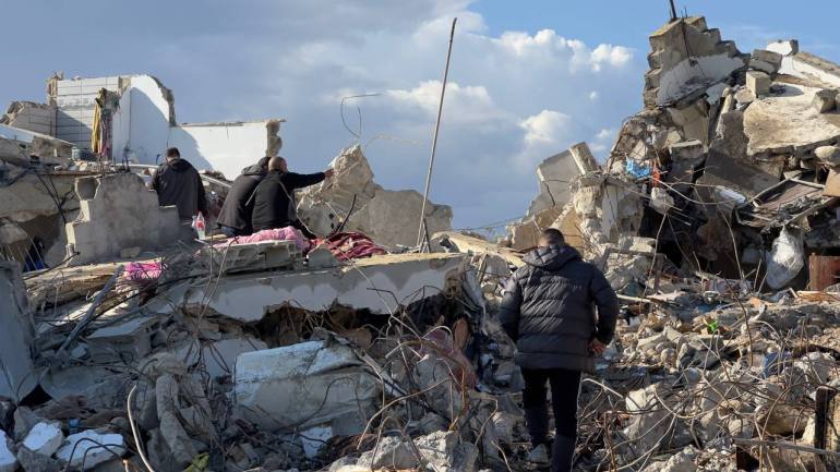 Des habitants inspectent une maison détruite par l’occupation après que des résistants s’y soient retranchés