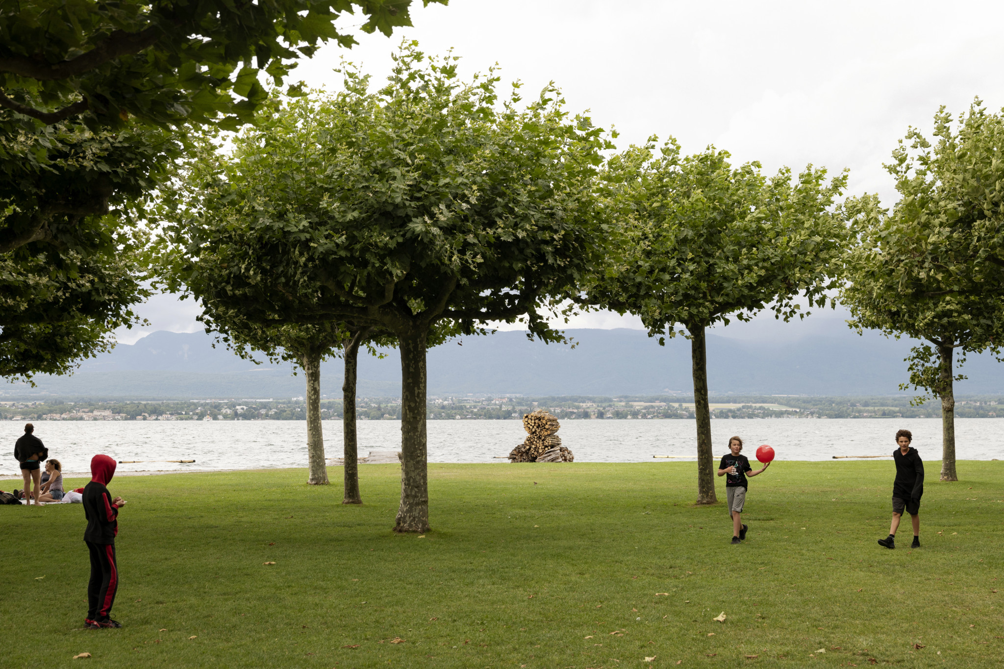 Des enfants à Hermance Des enfants jouent avec un ballon rouge sur une pelouse près du lac, entourés d’arbres, à Hermance, un village à la frontière franco-suisse, un jour de 1ᵉʳ août.