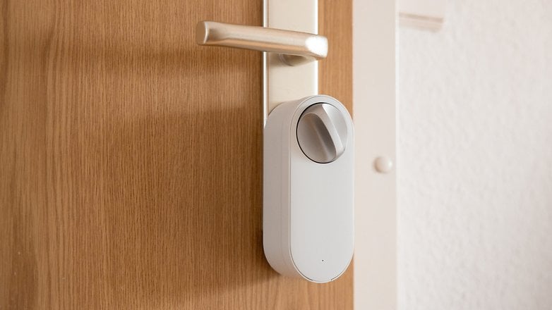 Serrure intelligente installée sur une porte en bois avec une poignée en argent.