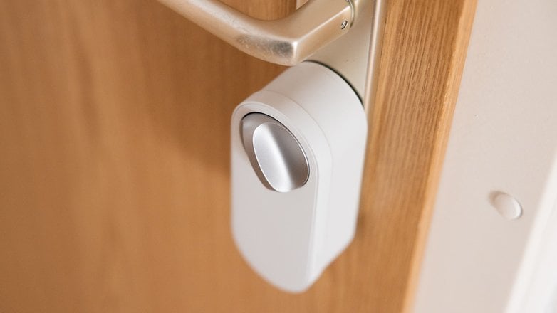 Gros plan de la serrure de porte intelligente Aqara U200 Lite montée sur une porte en bois.