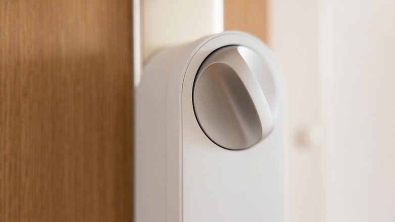 Gros plan d'un bouton de serrure de porte intelligente Aqara U200 Lite sur une porte en bois.