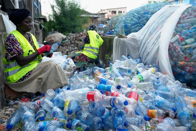 Ouvriers grattant des étiquettes sur des bouteilles en plastique