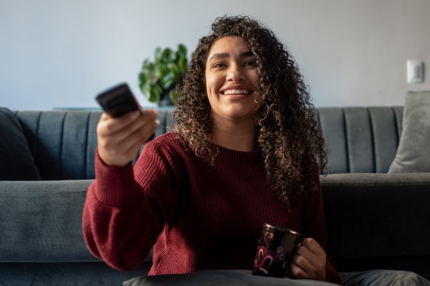jeune femme souriante regardant la télévision chez elle