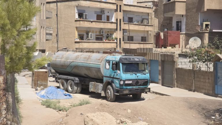 Camion citerne remplissant des réservoirs domestiques dans un quartier populaire d'Al-Qamishli