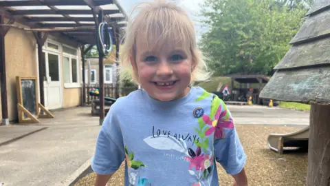 Ayda souriant au parc avec un t-shirt bleu