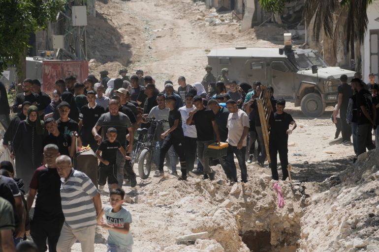 Habitants du camp de Toulkarim évacuant leurs maisons, portant leurs effets personnels