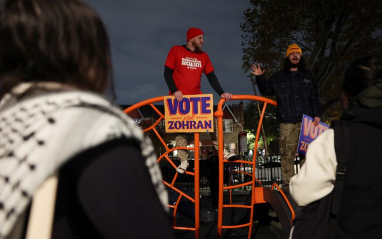 Attendees holding Vote for Zohran signs in Astoria