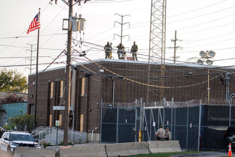 Agents masqués d'ICE observent la foule depuis le toit d'un centre de détention près de Chicago
